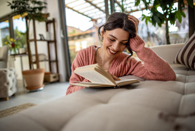 une femme lisant un livre posé sur un canapé