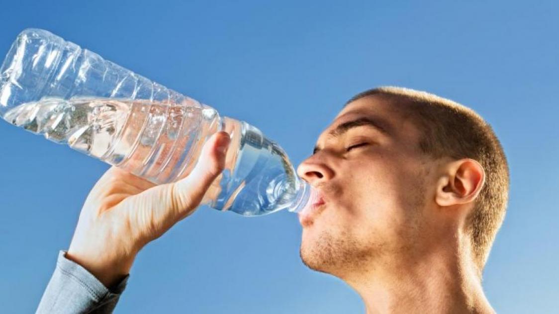 Un homme buvant de l'eau dans une bouteille en plastique
