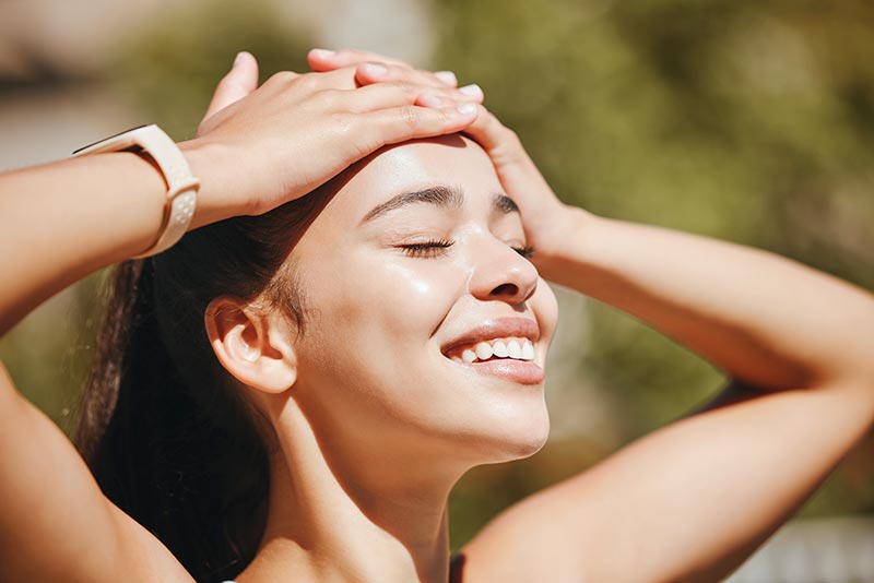 une femme à la peau saine se touche le front avec ses mains