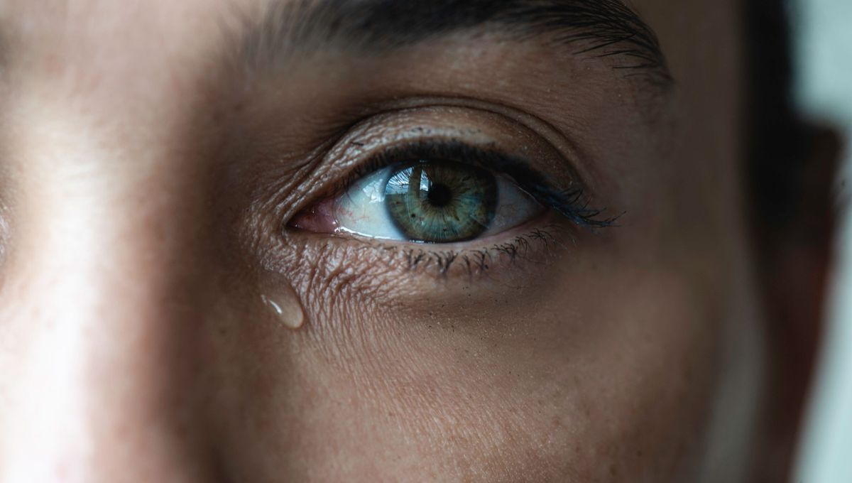 une larme coule sous les yeux d'une jeune femme aux yeux turquoises