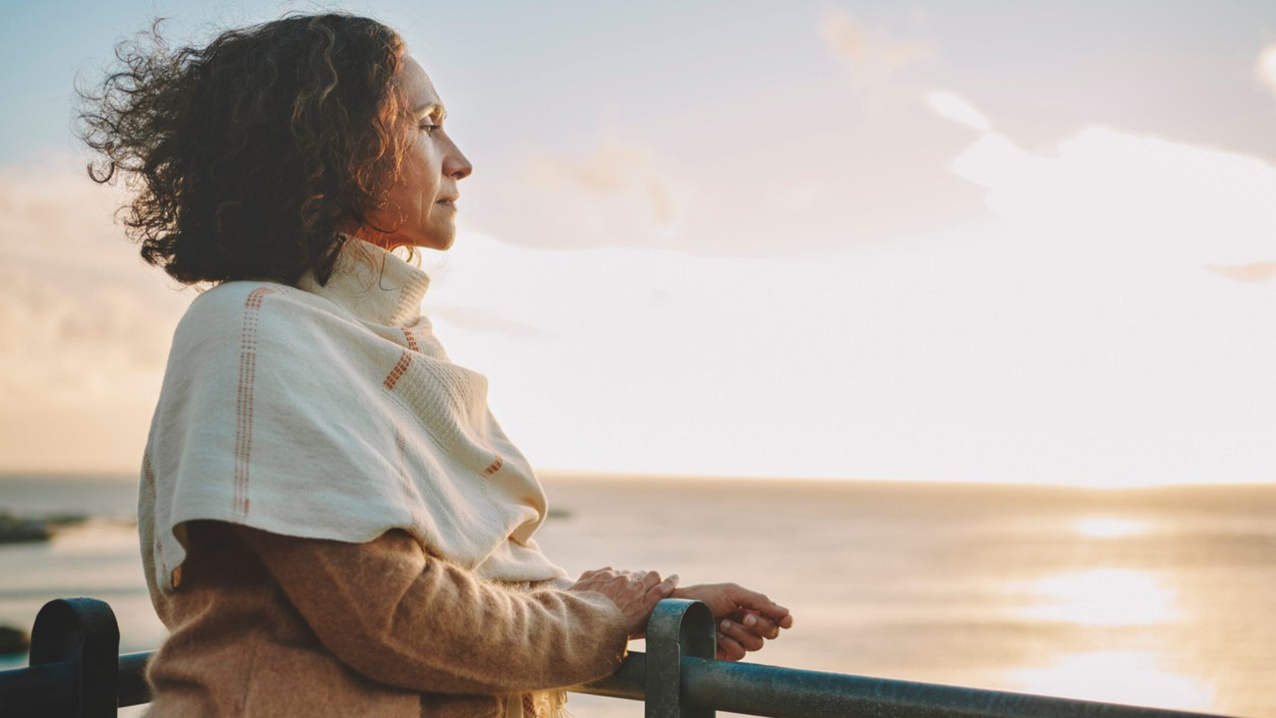 Une femme regarde un coucher de soleil tout en réfléchissant